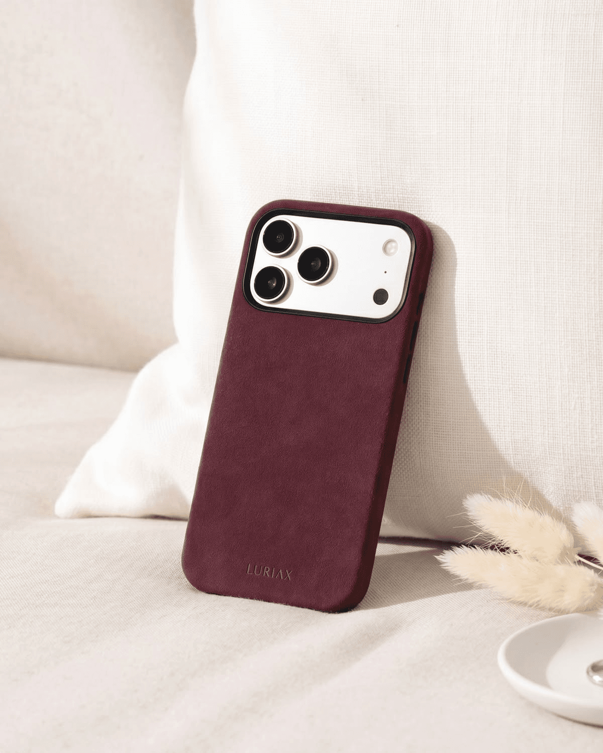 Burgundy leather phone case on soft bedding